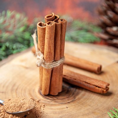 front-view-cinnamon-sticks-cinnamon-powders-pinecone-wood-board-dark